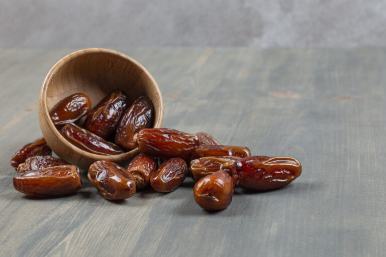 Sweet dates out of wooden bowl on marble background